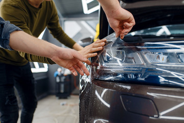 Workers applies car protection film on fender