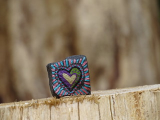 Ein auf einem besonderen Stein gemaltes Herz, platziert auf einem Baumstumpf mitten im Wald.
Was...