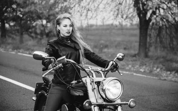 Woman posing with motorcycle outdoors. Black and white photo of beautiful biker woman.