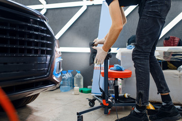 Male worker dries car protection film, auto tuning