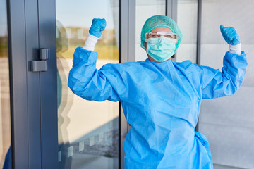 Surgeon in front of clinic clenches fists while cheering in coronavirus pandemic