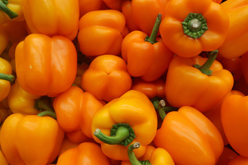 many ripe orange pepper fruits on a counter in a store