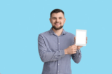 Young man with tablet computer on color background