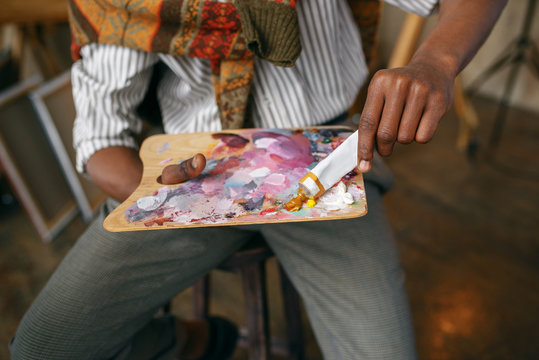 Male painter prepares colorful paints, art studio