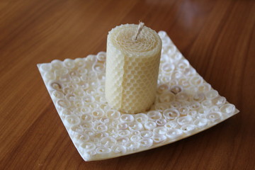 White candle without flame on the plate made of seashells