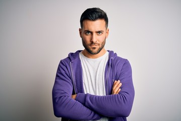 Young handsome man wearing purple sweatshirt standing over isolated white background skeptic and nervous, disapproving expression on face with crossed arms. Negative person.