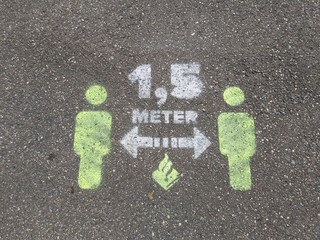 Social distancing sign on asphalt, on a road in the park, that represents keep safe distance, to prevent the coronavirus (COVID-19).