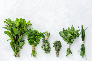 Assortment of fresh aromatic herbs from above on white background