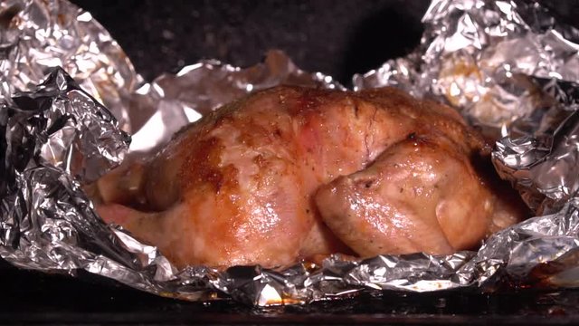Cooking roasted whole chicken in foil in hot oven closeup. Juicy tender chicken with golden skin. Cooking yourself during the coronovirus