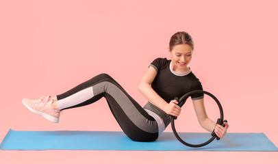 Sporty young woman training against color background