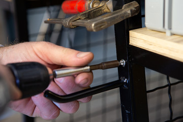 The hand of the master worker twists the screw to secure the shelf. He's in the store.