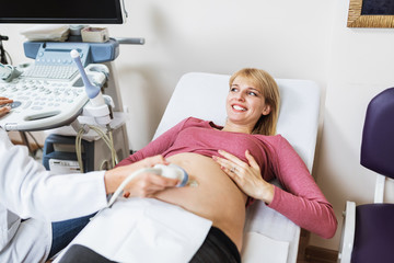 Obraz na płótnie Canvas Beautiful and happy expectant mother doing ultrasound scan in the prenatal clinic.