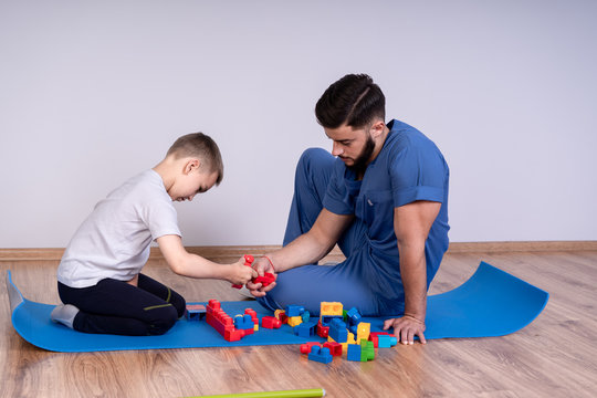 Male doctor with boy patient play educational game designer, the concept of rehabilitation of children