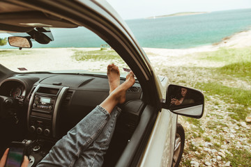 woman legs at car dashboard sea on background