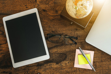 Close up top view of glasses, notebook and pen and papers on wooden table. Personal objects in a...