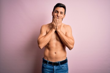 Fototapeta premium Young handsome strong man with beard shirtless standing over isolated pink background laughing and embarrassed giggle covering mouth with hands, gossip and scandal concept