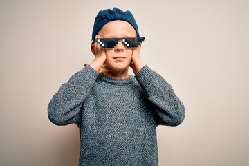 Young little caucasian kid wearing internet meme thug life glasses over isolated background suffering from headache desperate and stressed because pain and migraine. Hands on head.