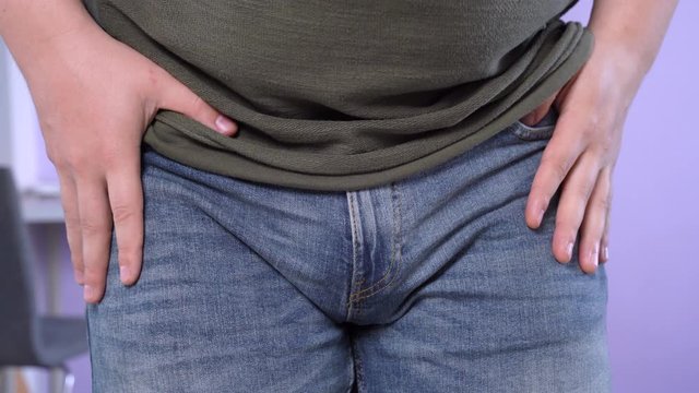 Man in jeans claps palms on knees and frantically searches his pockets with hands, close up. Forgetful guy lost keys to the house or car, documents, wallet or smartphone.