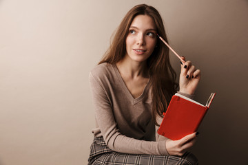 Photo of caucasian charming woman thinking and holding diary