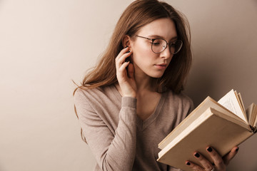 Photo of charming serious woman reading book and sitting on chair