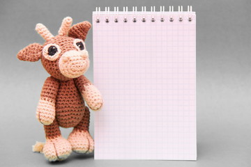The bull is the symbol of the New year 2021. A knitted brown toy bull next to a Notepad . Copy Space.