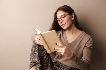 Photo of charming smiling woman reading book and sitting on chair