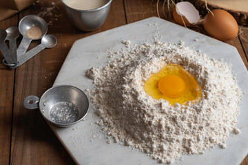 flour with yolk egg place on the wooden table for cooking something.
