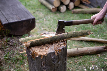 Lumberjack chopping wood for winter, Young man chopping woods with an axe. Detail of two flying pieces of wood on log with sawdust. Man is chopping wood with vintage axe. Frozen moment.