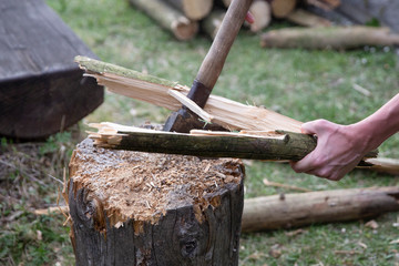 Lumberjack chopping wood for winter, Young man chopping woods with an axe. Detail of two flying pieces of wood on log with sawdust. Man is chopping wood with vintage axe. Frozen moment.