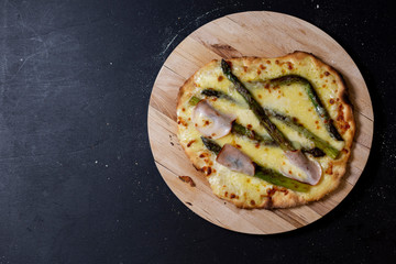 selbstgemachte Pizza mit Mascarpone, Mozzarella, Sauce hollandaise, grünem Spargel, Truthanschinken auf einer Seite, Studio