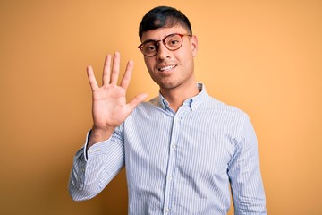 Young handsome hispanic business man wearing nerd glasses over yellow background showing and...