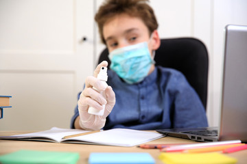 Distance learning online education. schoolboy in medical mask studying at home, working at laptop notebook and doing school homework. coronavirus quarantine