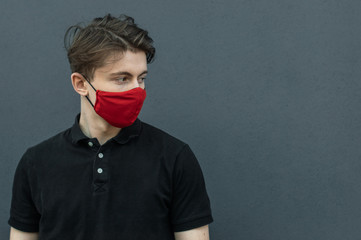 Portrait of guy in black t-shirt and red mask on his face for protect and stop viruses and coronavirus pandemic, covid-19 outbreak