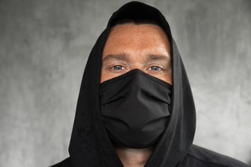 Fototapeta na wymiar A man in a hood and a white medical mask
