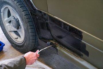 close up of a man painting an army jeep and adding black trim