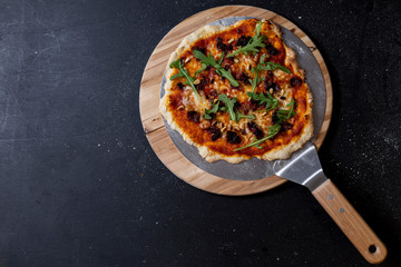 selbstgemachte Pizza mit Tomatensauce, Mozzarella, gebratener Speck und Zwiebeln, Rucola und Pinienkerne, Studio