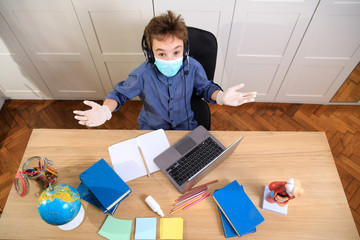 Distance learning online education. A schoolboy boy studies at home and does school homework. A home distance learning , Coronavirus pandemic in the world. Closing schools