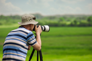 Obraz premium Man in a hat taking a picture at summer. Place for text.