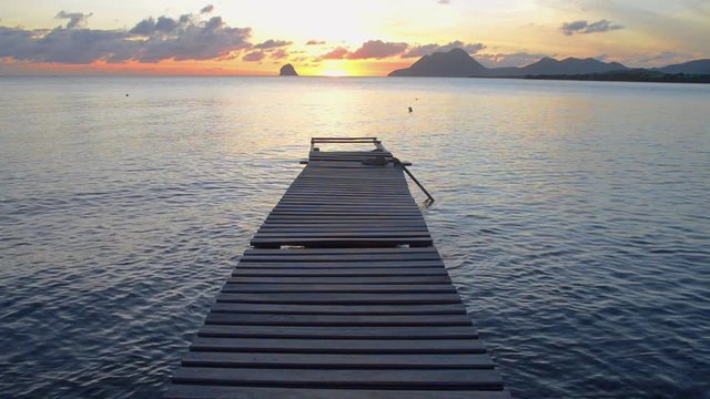 coucher du soleil sur un ponton de bois au milieu d'un baie de Martinique