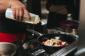 Professional chef in kitchen restaurant preparing meat and vegetable.