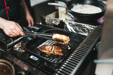 Professional chef in kitchen restaurant preparing meat.