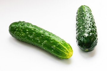 two whole green cucumbers on a white background macro shot