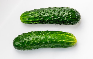 two whole green cucumbers on a white background macro shot