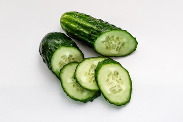 green cucumber cut into pieces on a white background macro shot