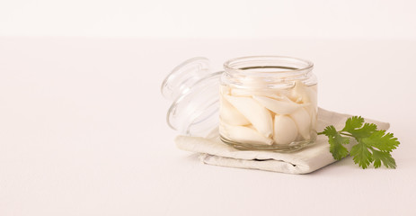 fermented garlic in a opend transparent jar on a white table. Decorated with cilantro
