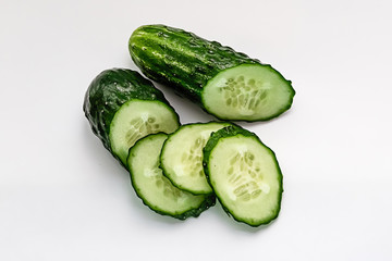 green cucumber cut into pieces on a white background macro shot