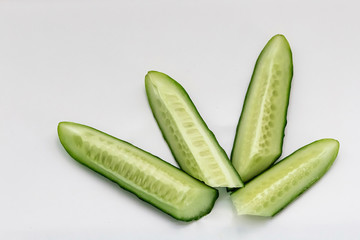 green cucumber cut into pieces on a white background macro shot