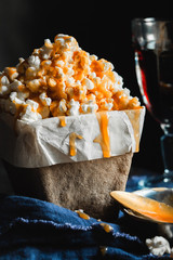 A bowl of popcorn with salted caramel, a glass with cola on a black background. Leisure.