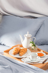 Fototapeta na wymiar Breakfast in bed, a tray of coffee, croissants, jam. Honeymoon. Early morning at the hotel.