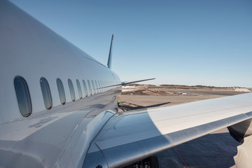 Fototapeta na wymiar Wing of airplane with windows on runway